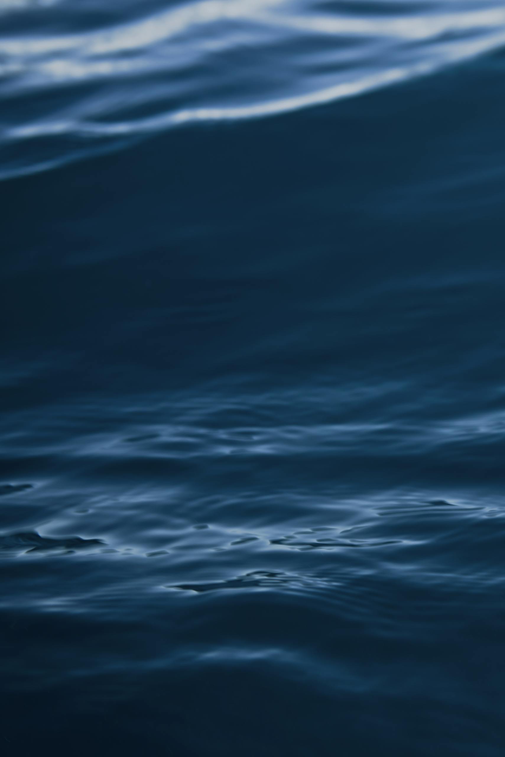 A tranquil view of dark blue ocean waves with gentle ripples and motion.